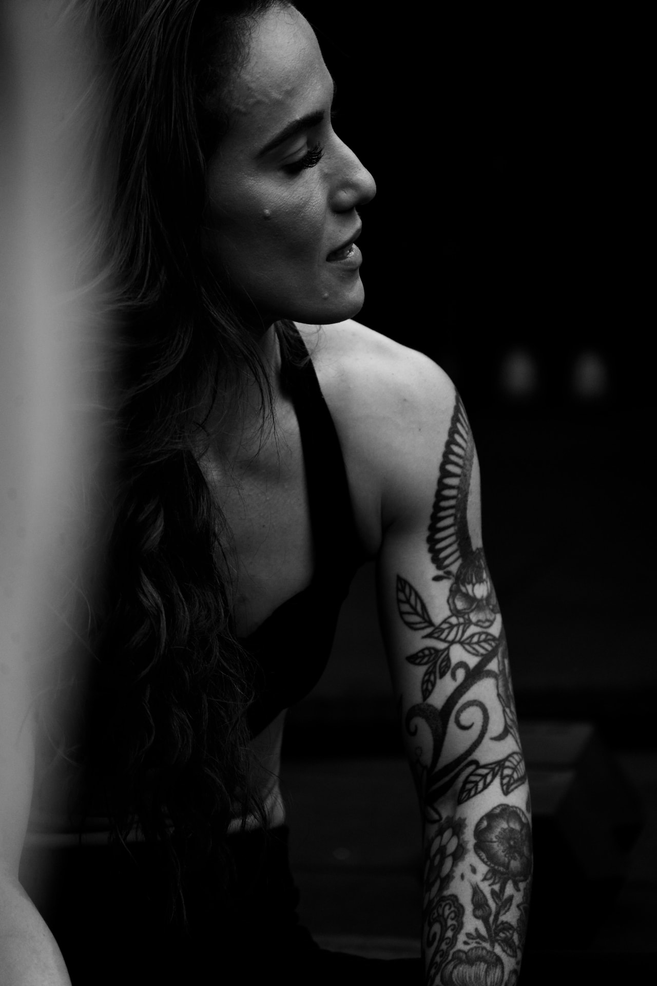 Portrait de profil d'une femme au bras entièrement tatoué, photographie noir et blanc